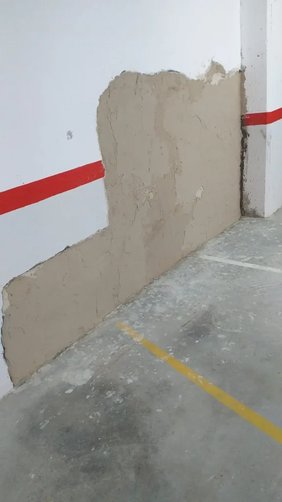 Pared de parqueadero en proceso de reparación por humedad